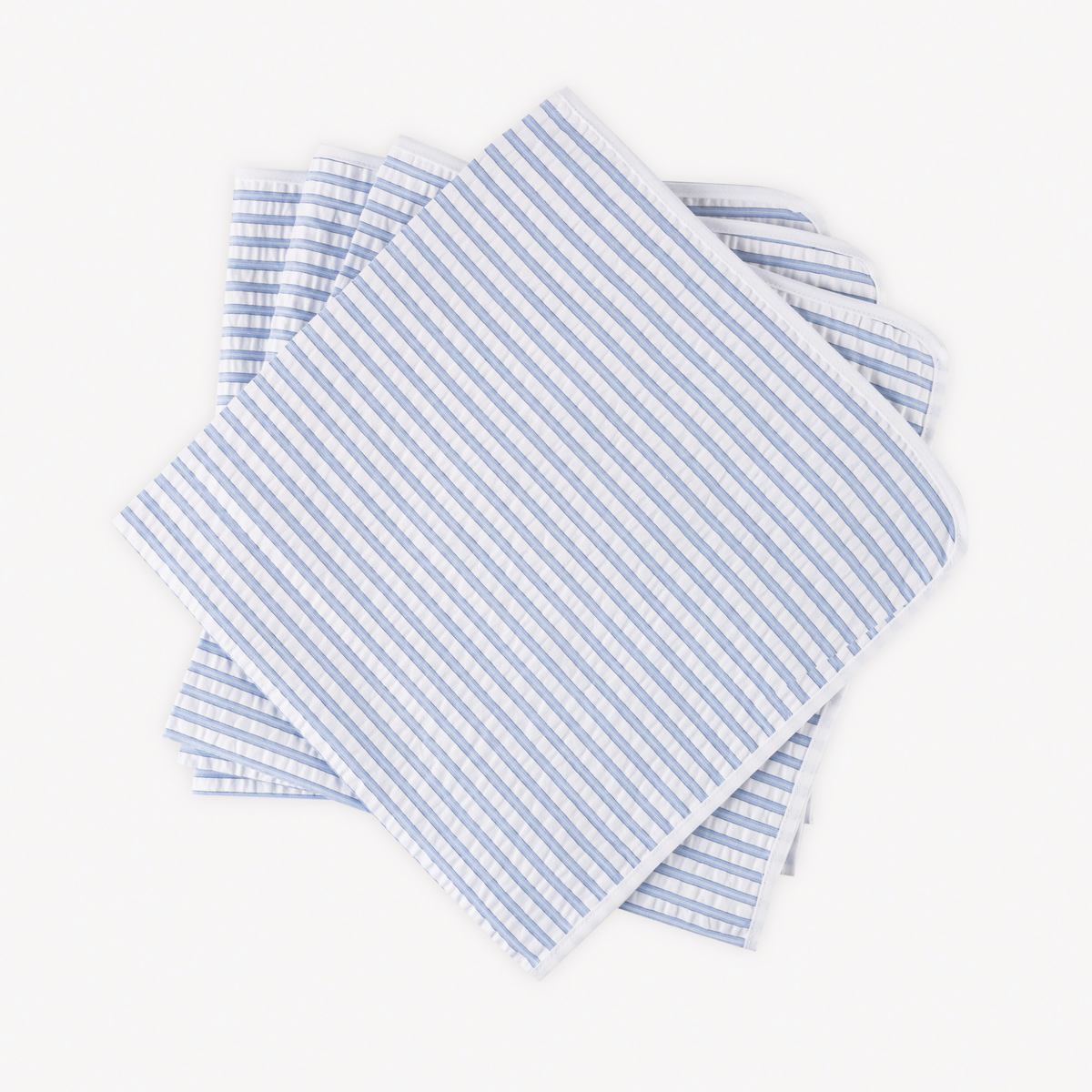 Four neatly stacked Matouk Matteo Table Napkins in Azure color