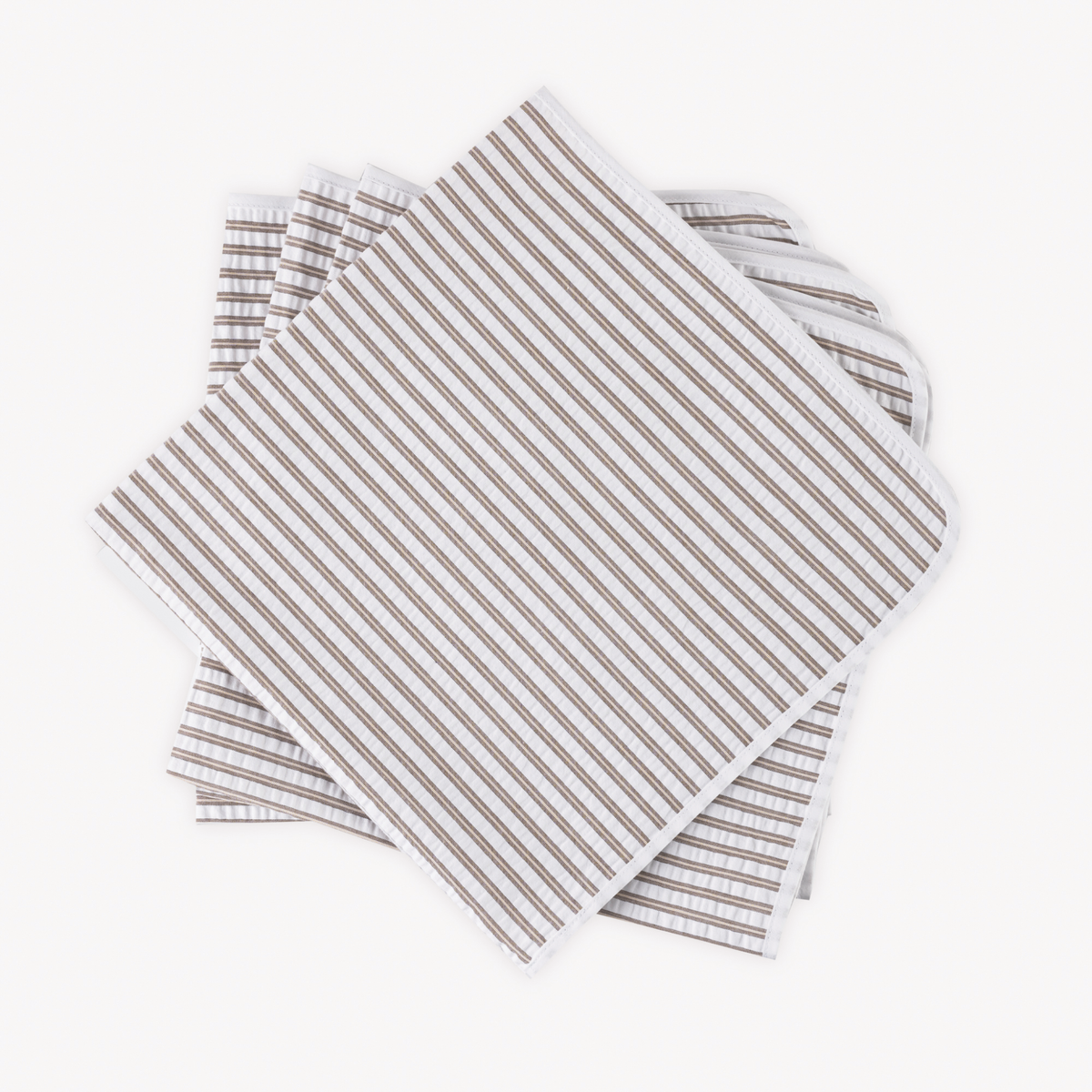 Four neatly stacked Matouk Matteo Table Napkins in Bark color