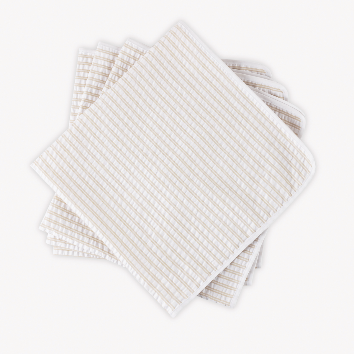 Four neatly stacked Matouk Matteo Table Napkins in Natural color