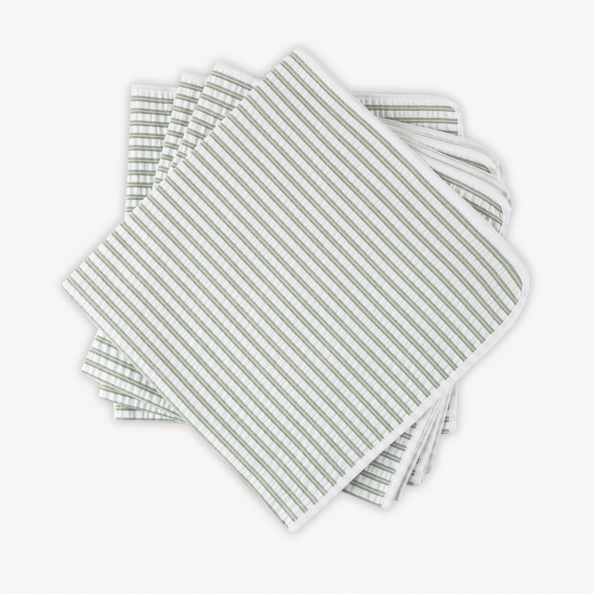 Four neatly stacked Matouk Matteo Table Napkins in Palm color