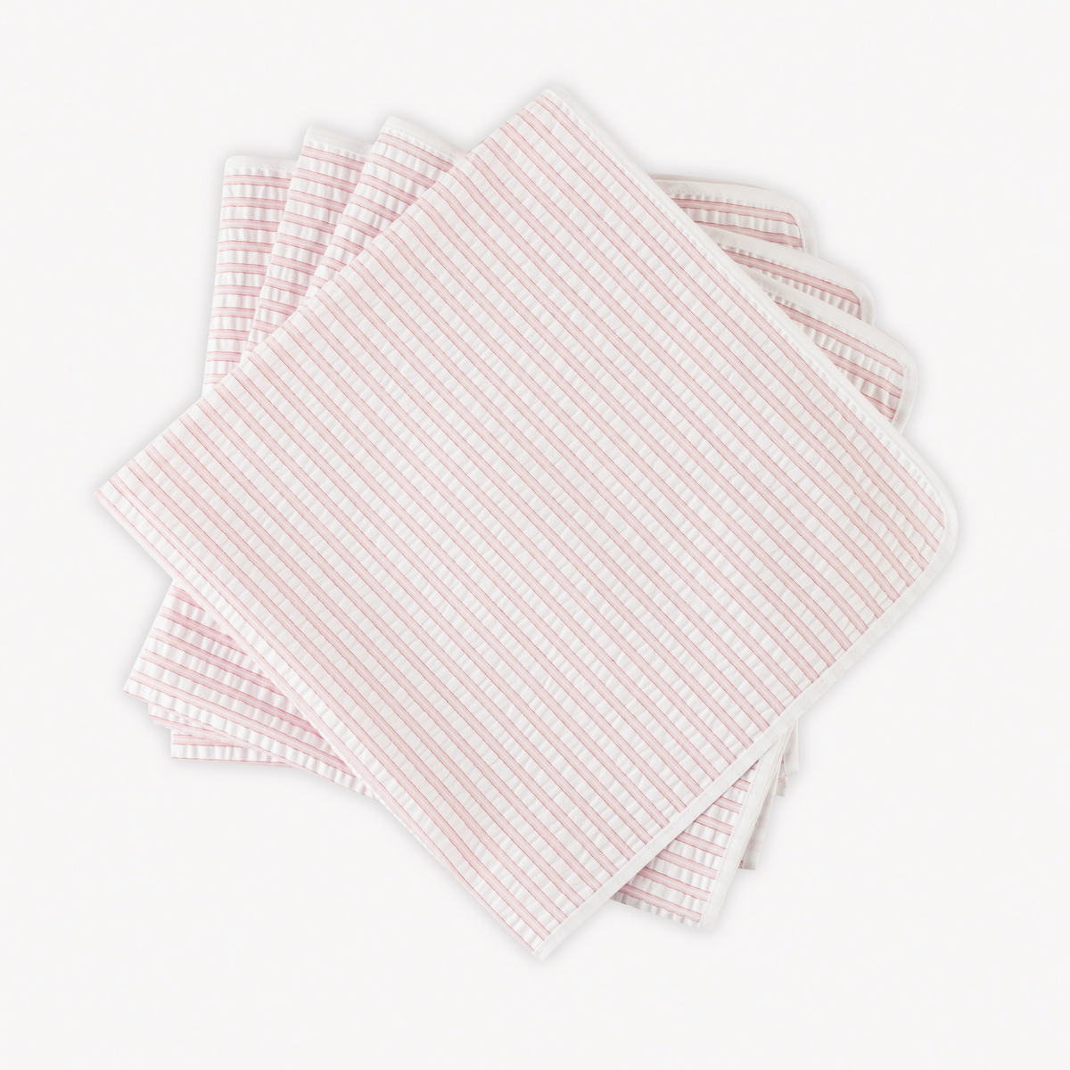 Four neatly stacked Matouk Matteo Table Napkins in Pink color