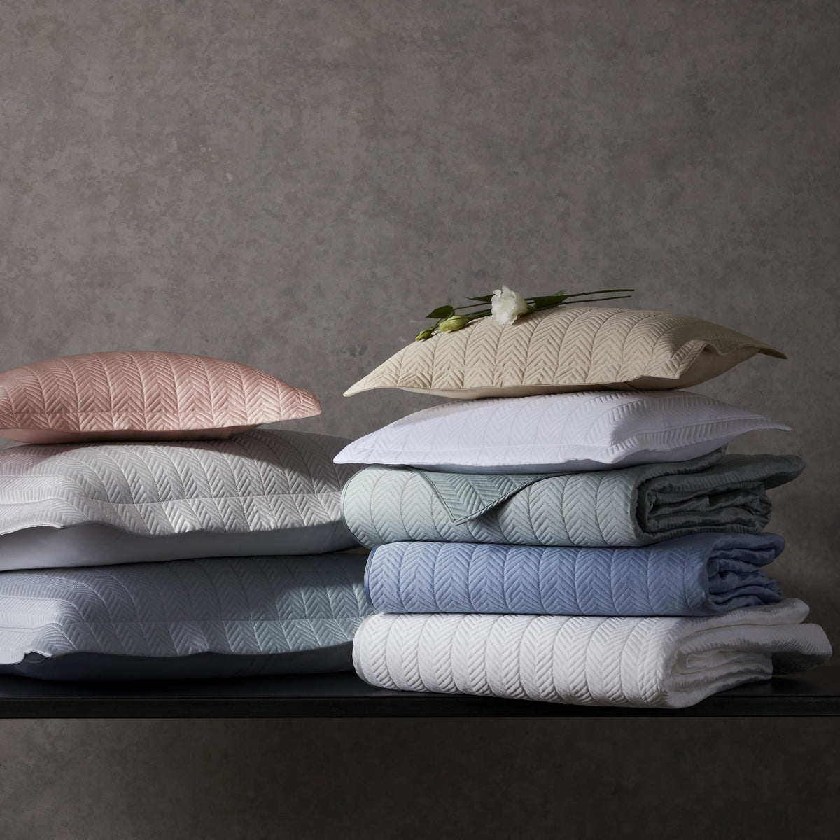 Lifestyle Shot of Stacks of Matouk Netto Bedding in Different Colors