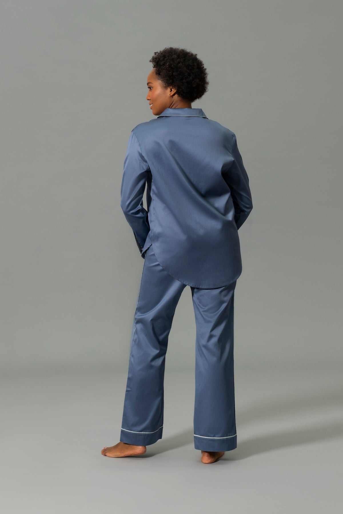 Back View of Model Wearing Matouk Nocturne Pajama Set in Color Steel Blue and Dove