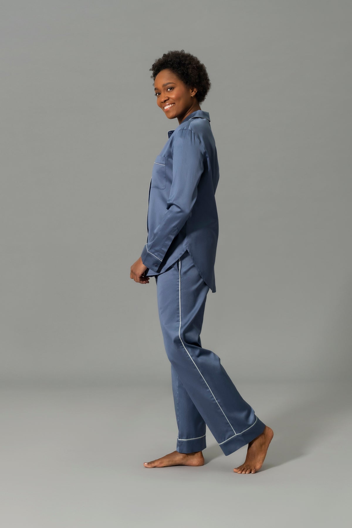 Side View of Model Wearing Matouk Nocturne Pajama Set in Color Steel Blue and Dove