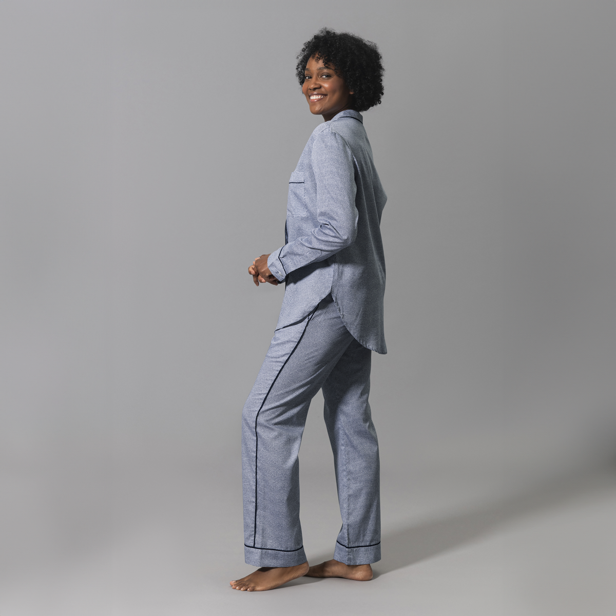 Side Angle of a Woman Wearing a Matouk Jasper Pajama Set in Steel Blue and Navy Color