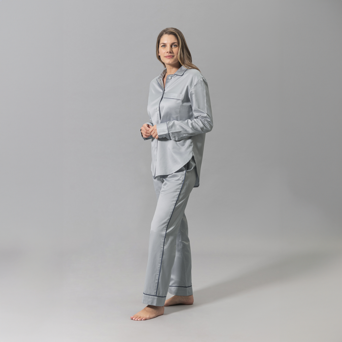 Angled Look of a Woman Wearing a Matouk Nocturne Pajama Set in Dove Steel and Blue