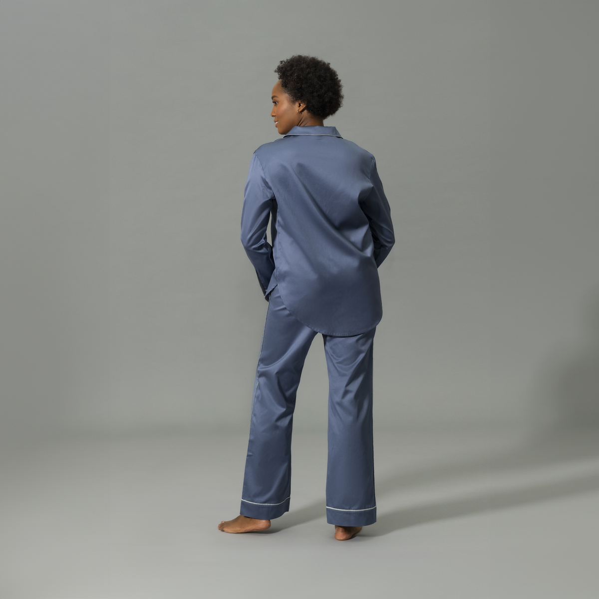 Behind View of Model Wearing Matouk Nocturne Pajama Set in Color Steel Blue and Dove