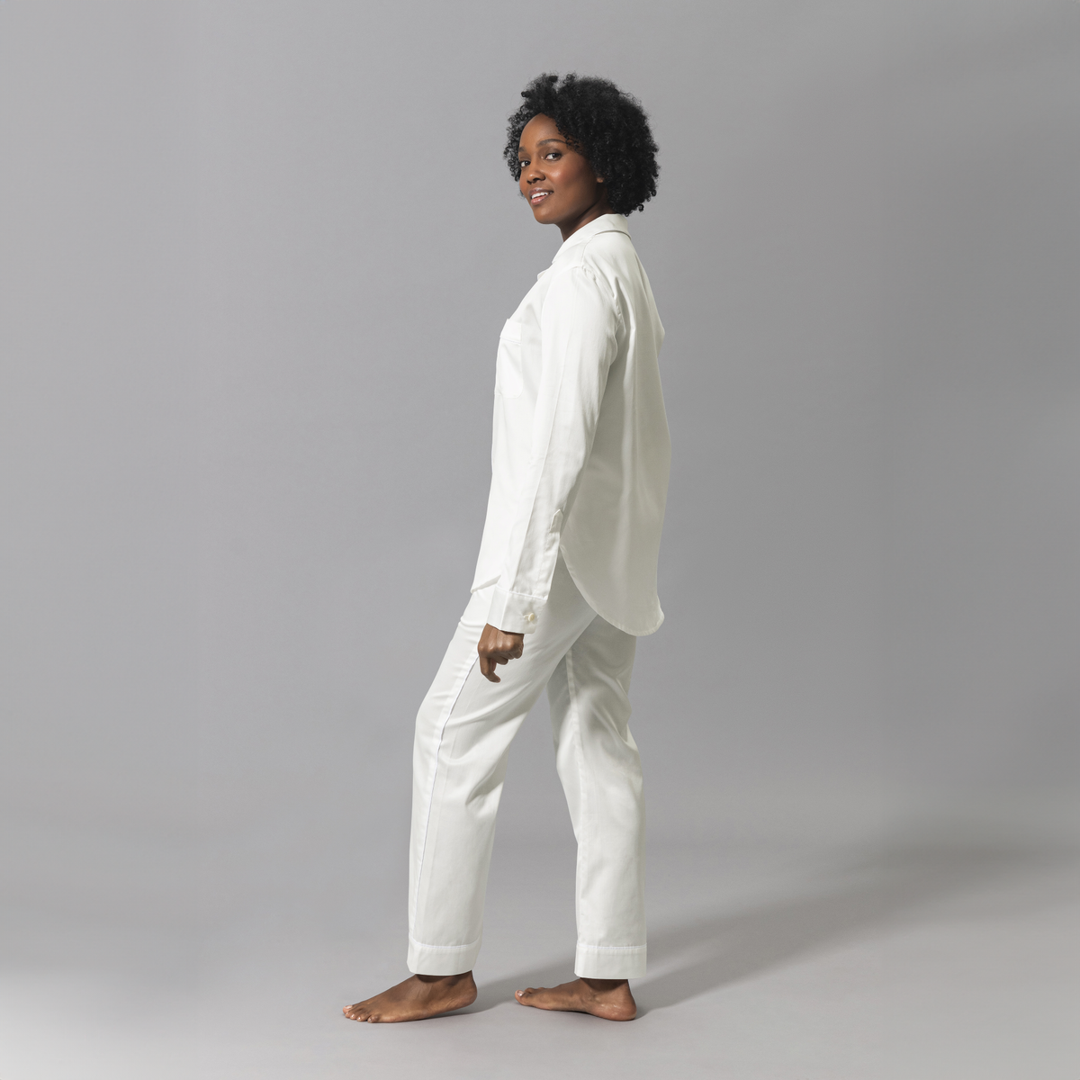 Angled Look of a Woman Wearing a Matouk Nocturne Pajama Set in Bone and White