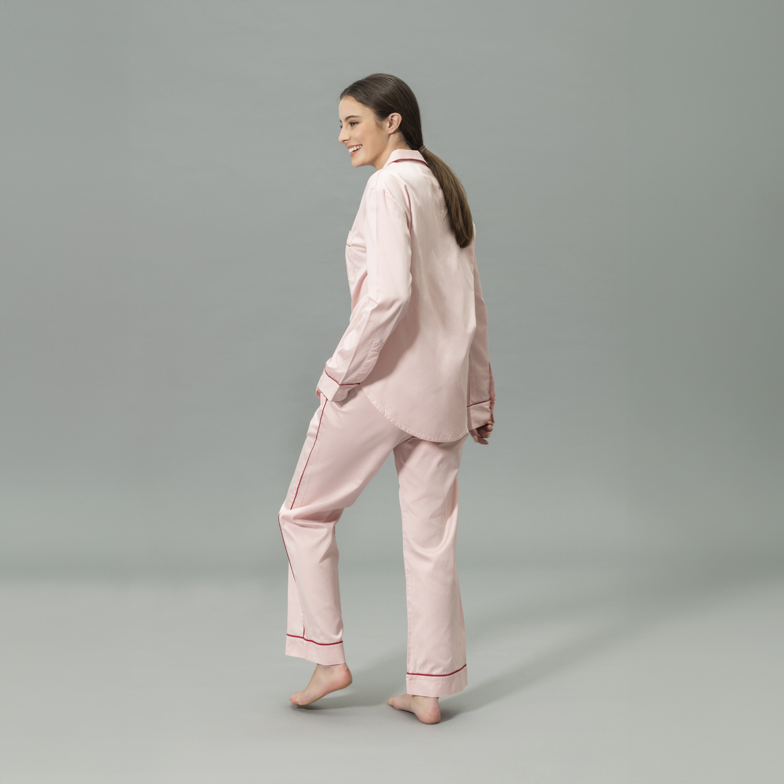 Side View of Model Wearing Matouk Nocturne Pajama Set in Color Pink and Scarlet