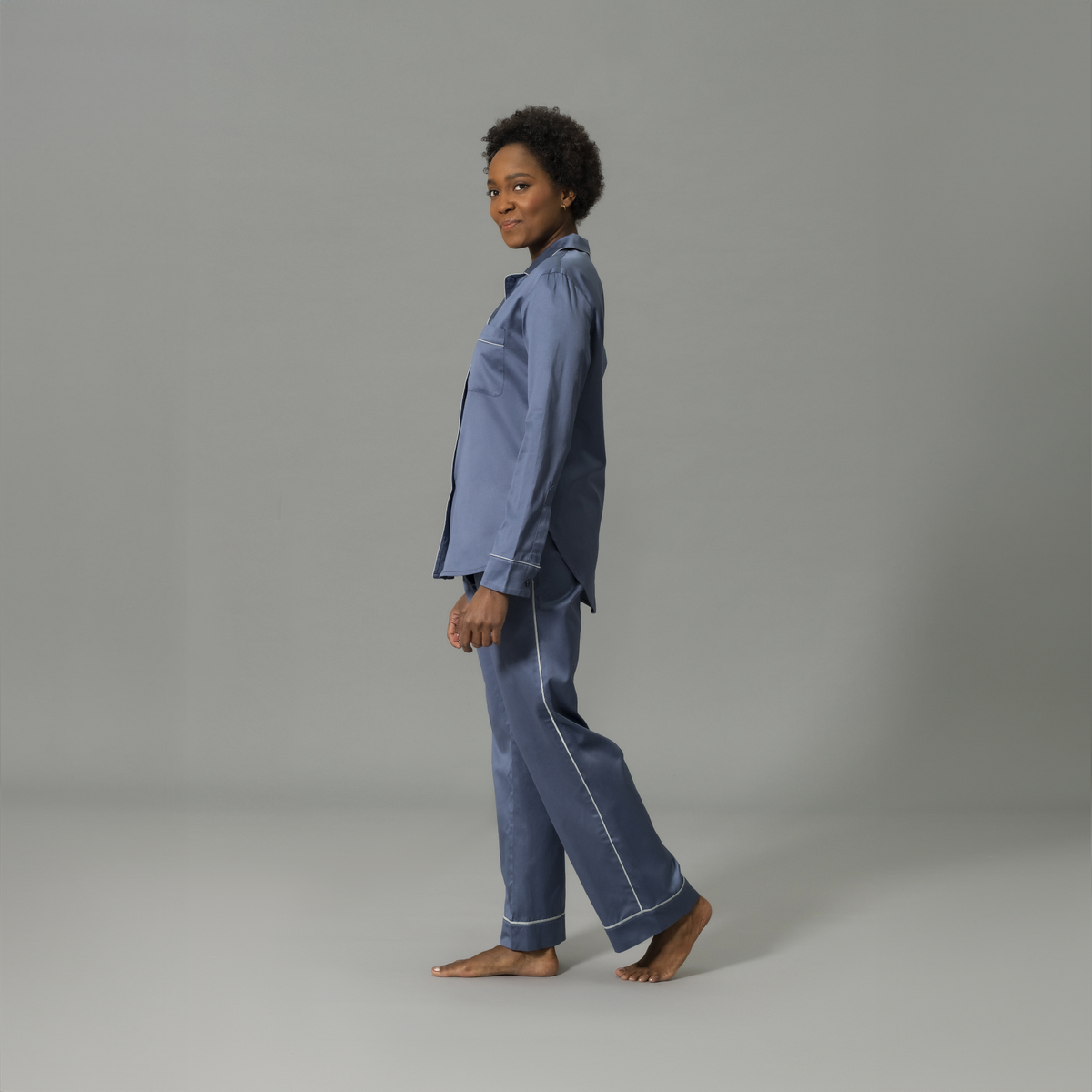 Side View of Model Wearing Matouk Nocturne Pajama Set in Color Steel Blue and Dove