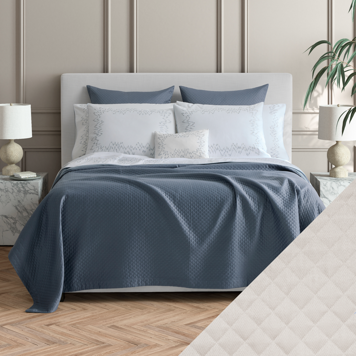 Made bed with Matouk Petra matelassé bedding, with a Silver swatch in a neutral-toned bedroom.