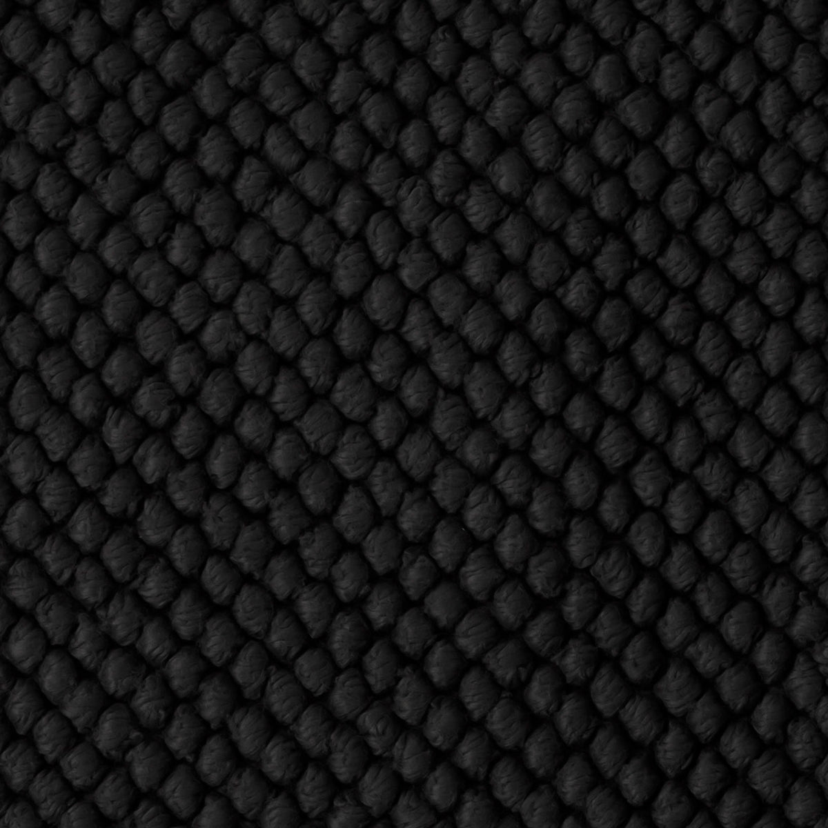 Close-up of a black, textured woven fabric of the Matouk Reverie bath rug