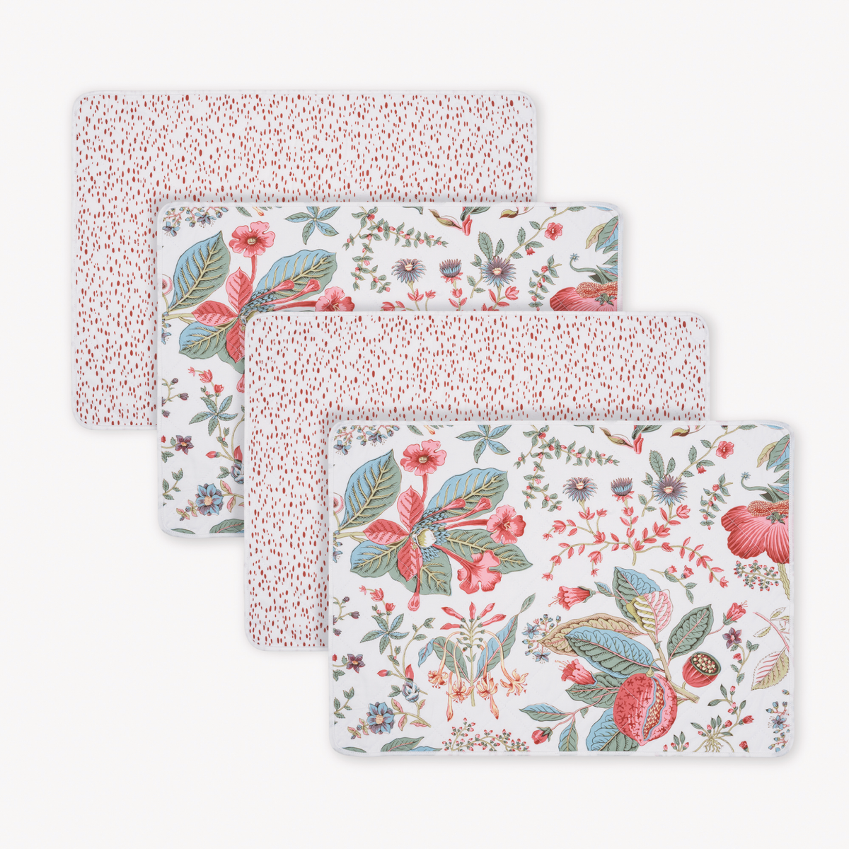 Four rectangular reversible placemats: two with red dots, two with a botanical design in red, blue, and green.