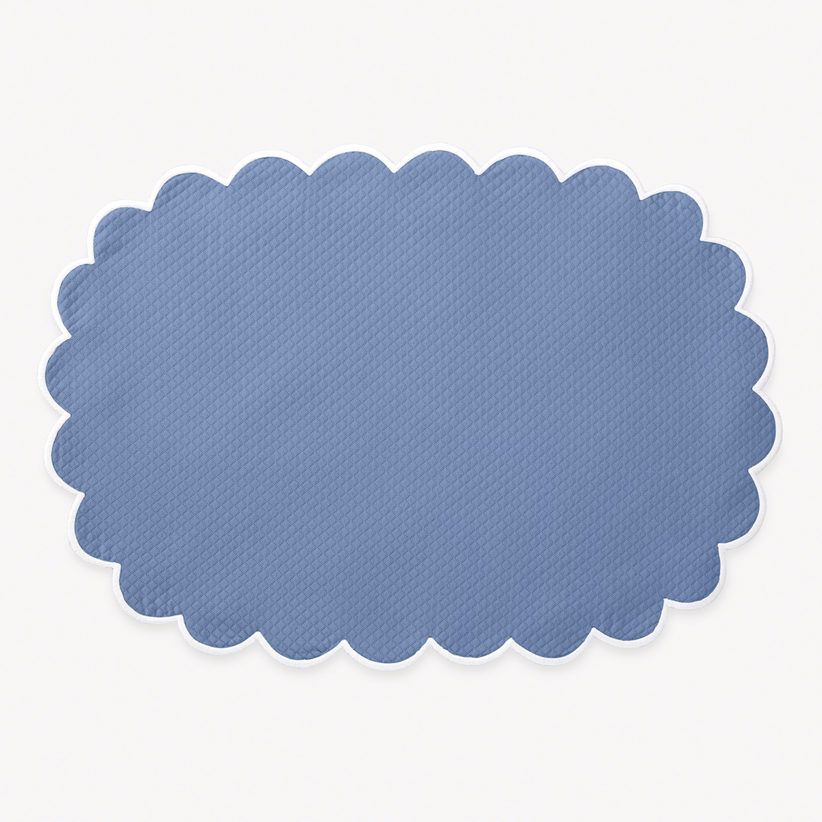 Azure oval placemat with a scalloped edge from Matouk Savannah Gardens table linens