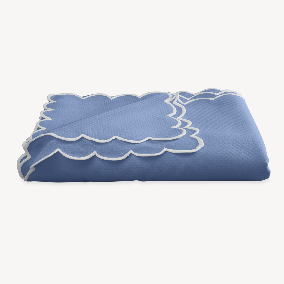 A folded Azure Matouk Savannah Gardens Tablecloth on a white background