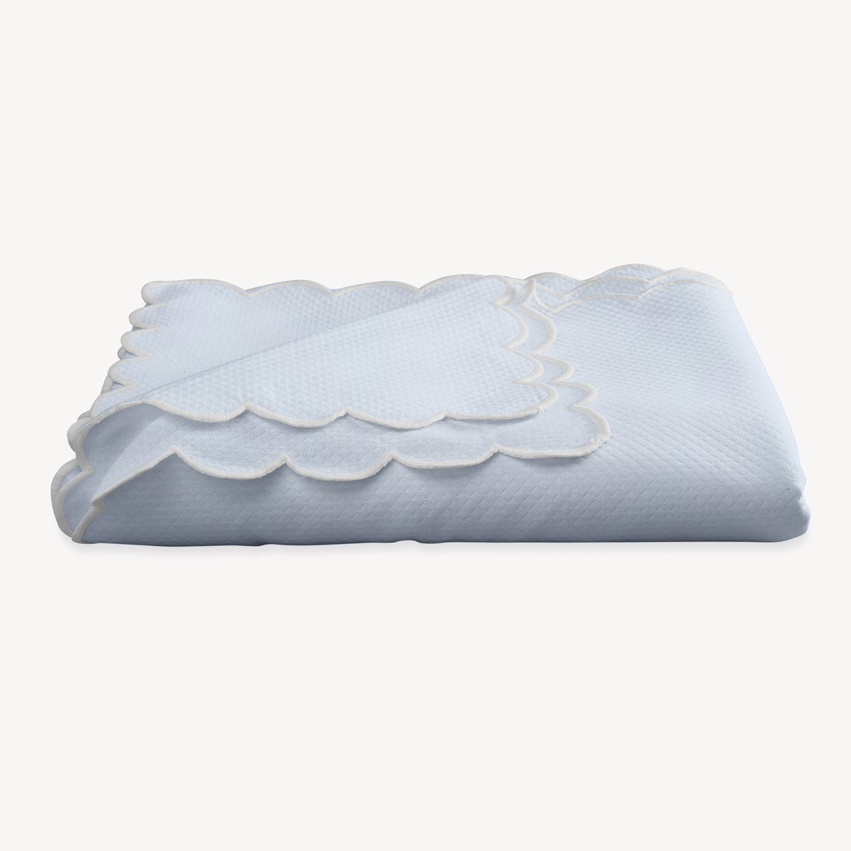 A folded Light Blue Matouk Savannah Gardens Tablecloth on a white background