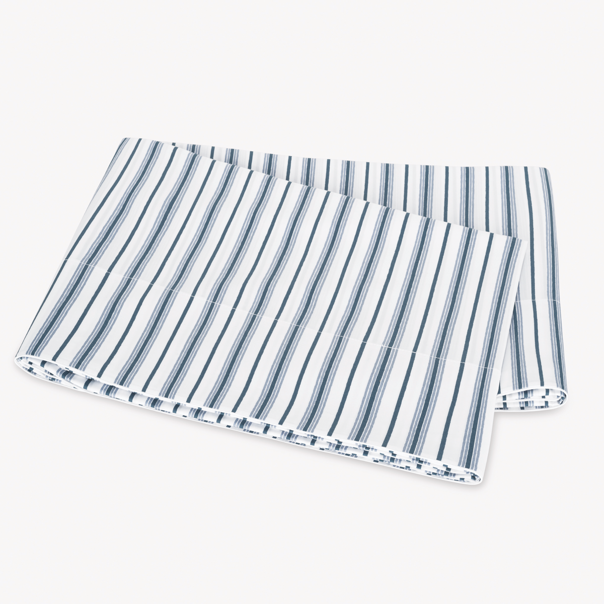 Folded Prussian Blue Matouk Calypso Flat Sheet on a plain white surface
