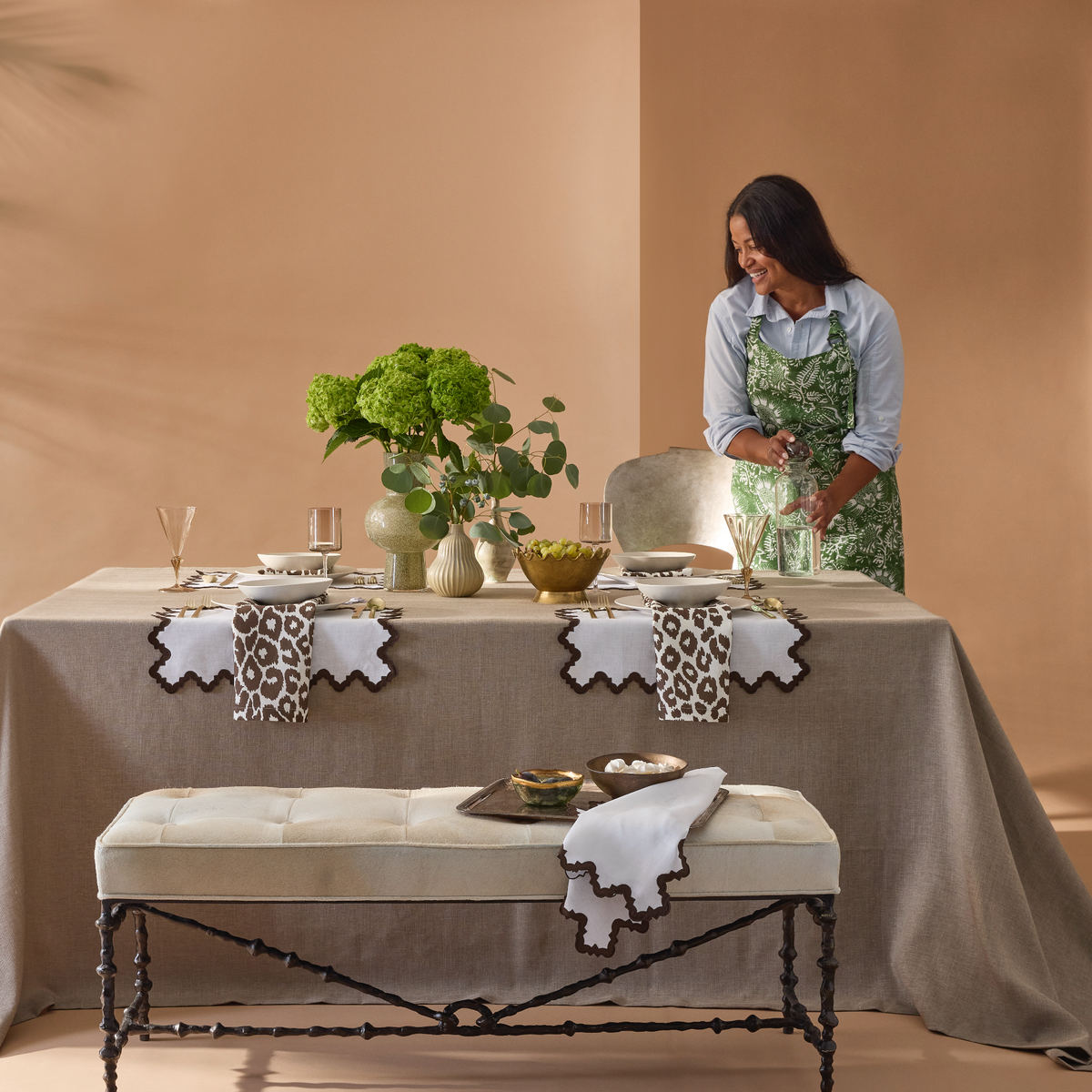 Kitchen Lifestyle Shot of Matouk Schumacher Linen Apron in Granada Palm Pattern with Model