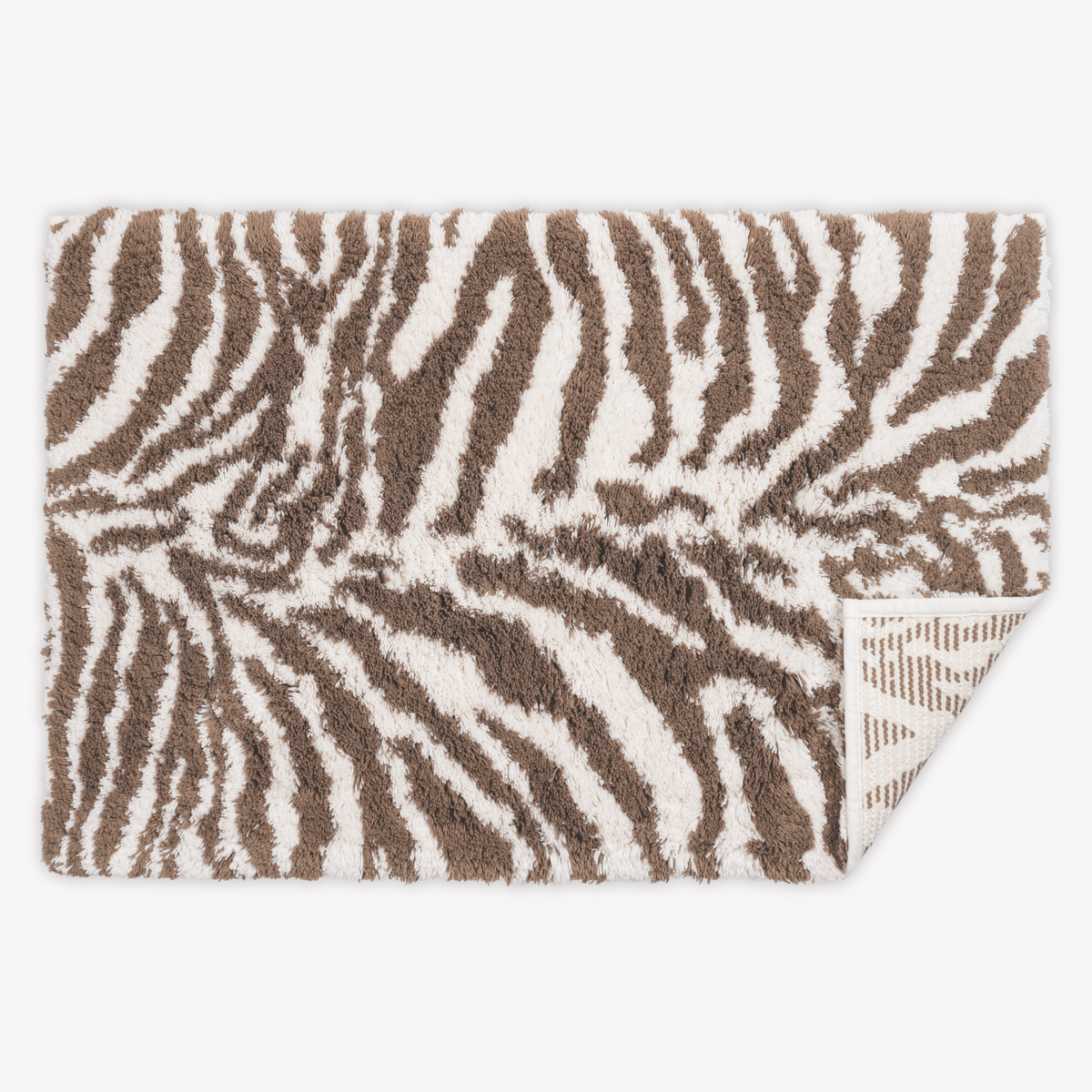 Top view of Matouk Schumacher Regine Bath Rugs in Sable color with one tip folded
