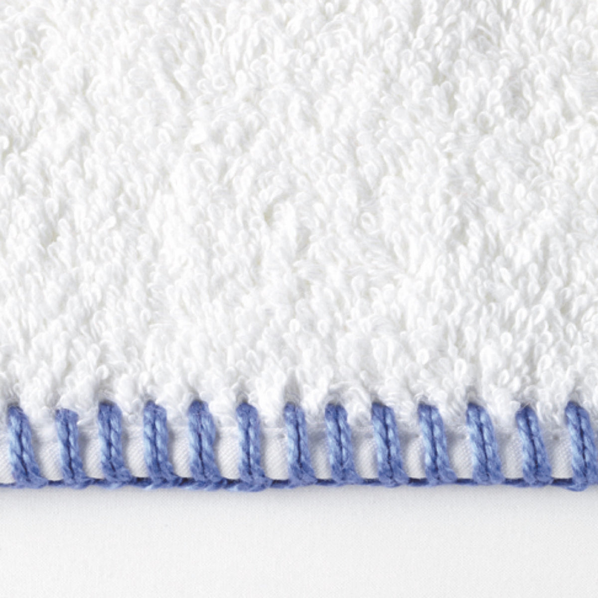 White Matouk Whipstitch bath towel with blue stitched edge, showcasing luxurious long-staple cotton texture and detail.