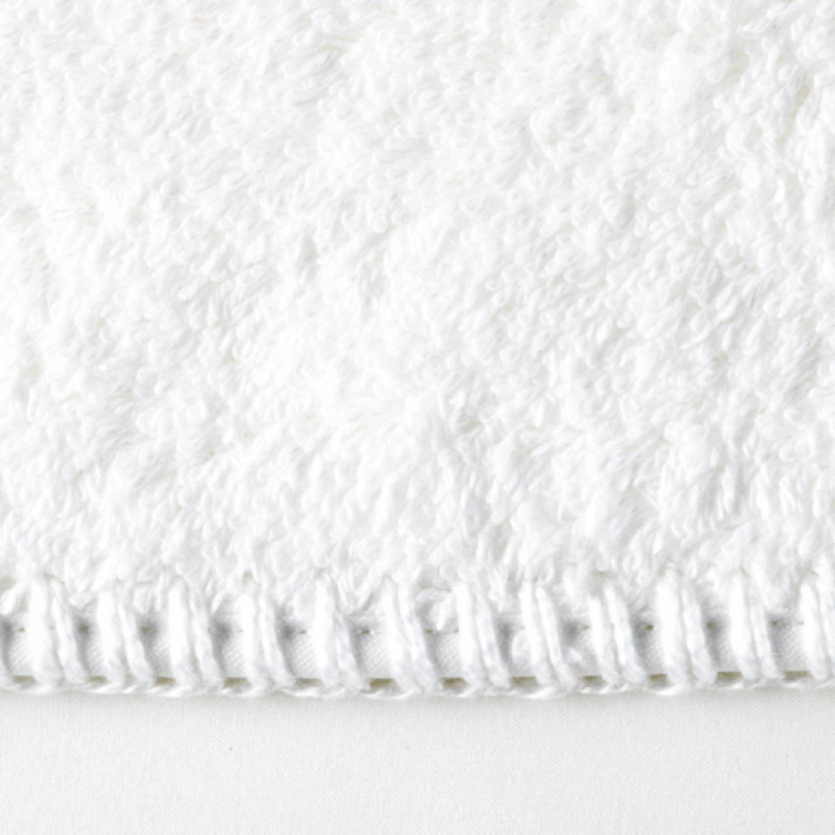 Close-up of the edge of a Matouk Whipstitch bath towel, crafted from Cairo long-staple cotton with visible stitching.