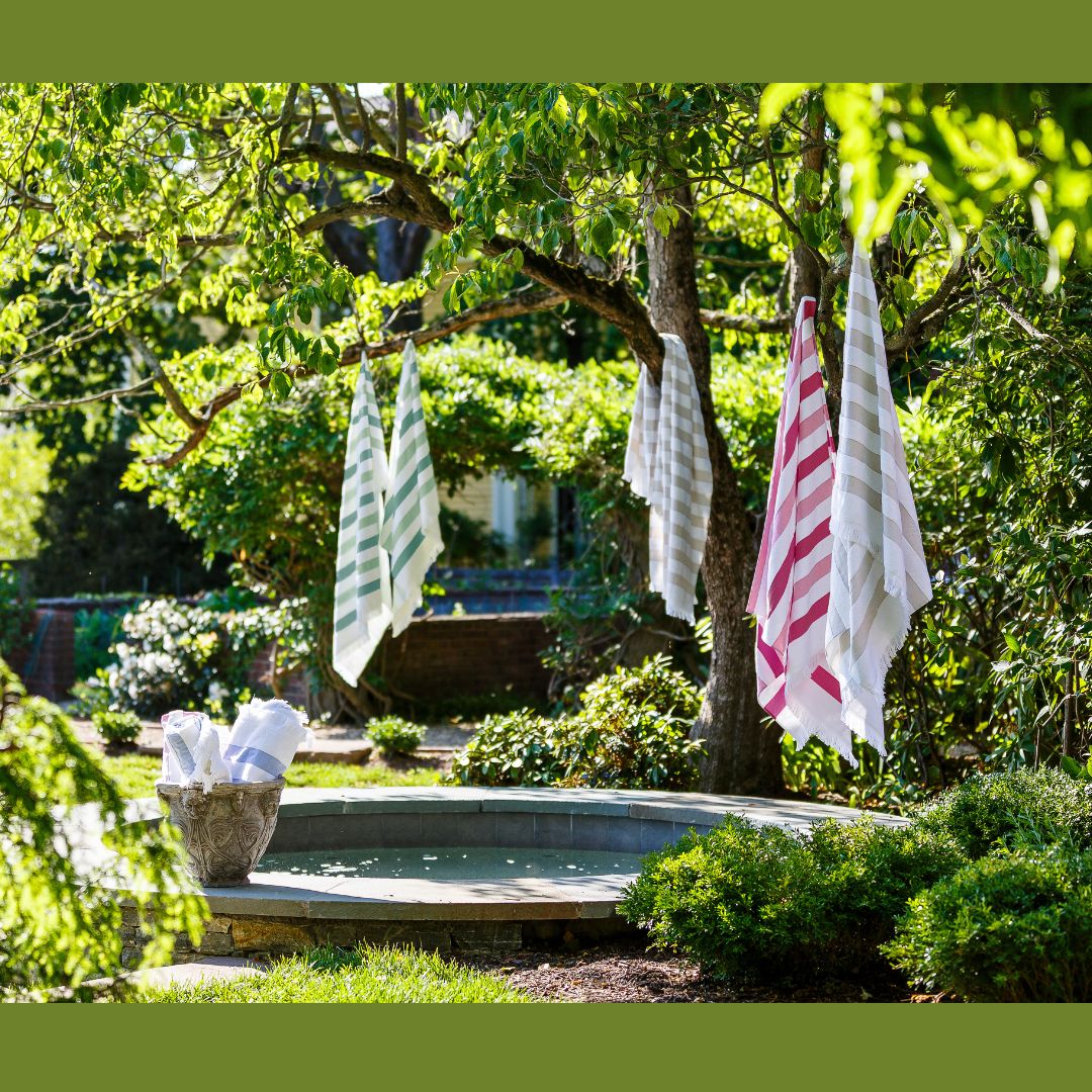 Matouk Amado Beach Towels hanging in a tree over a pool