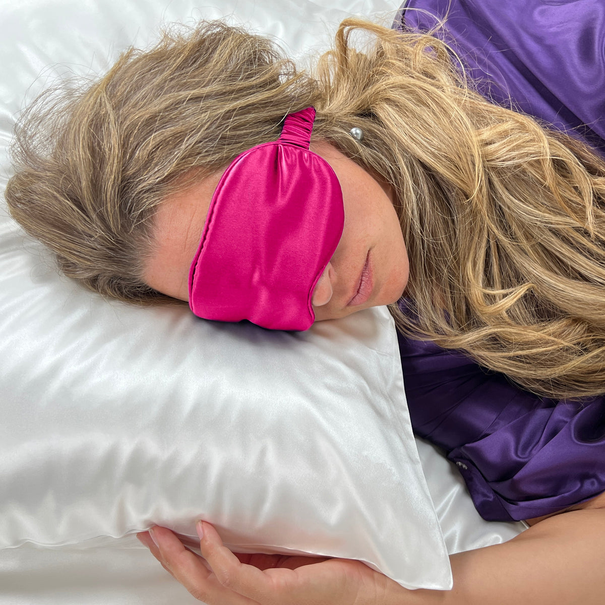 Woman sleeping on a white pillow with a Magenta silk sleep mask for eyes for ultimate comfort