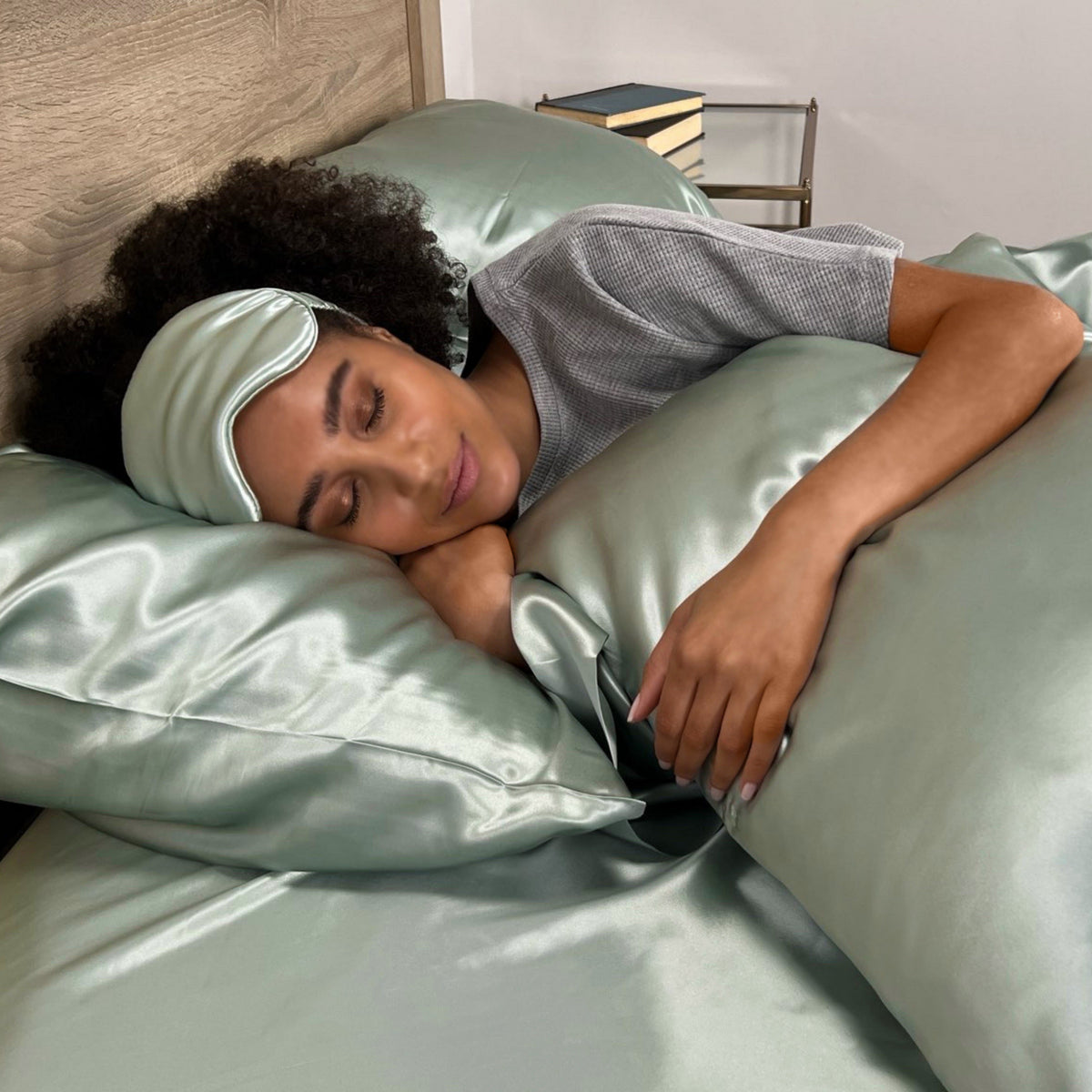 Woman sleeping peacefully on a sage pillow with a matching eye mask for ultimate comfort