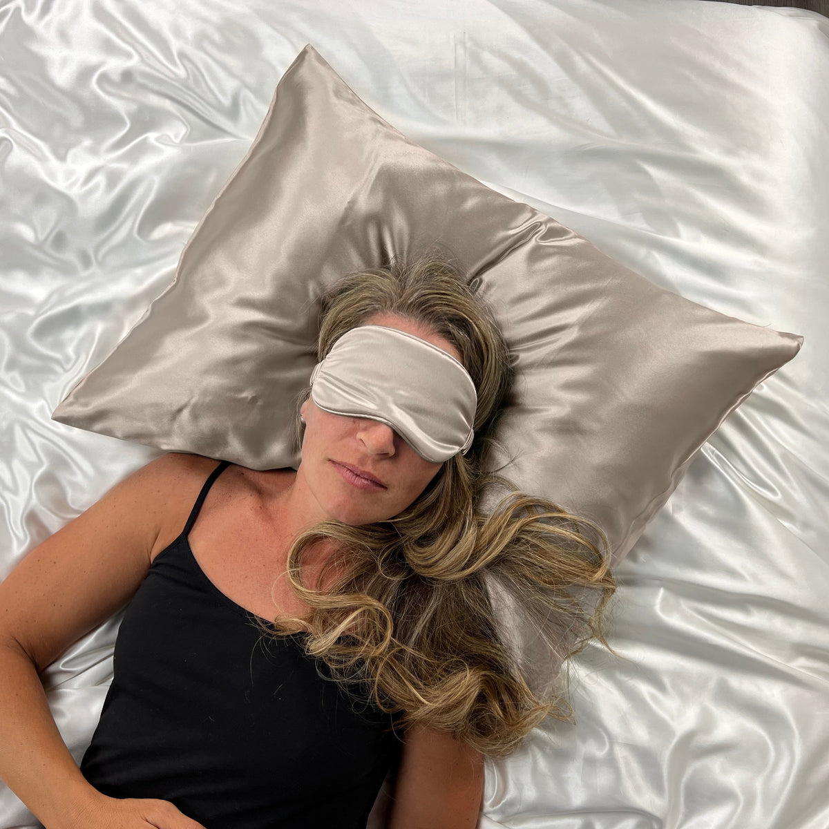 Woman sleeping on a Taupe pillow with a matching silk sleep mask for eyes for ultimate comfort