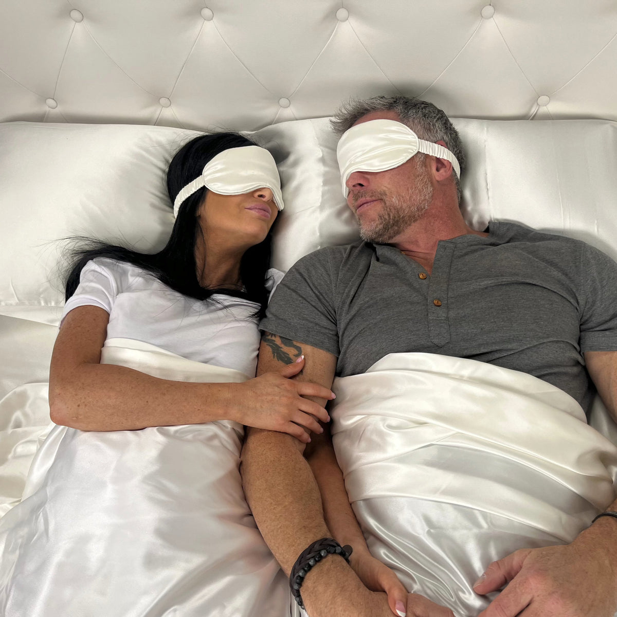 Couple sleeping peacefully on bed, wearing mulberry silk eye masks for deep, restful sleep