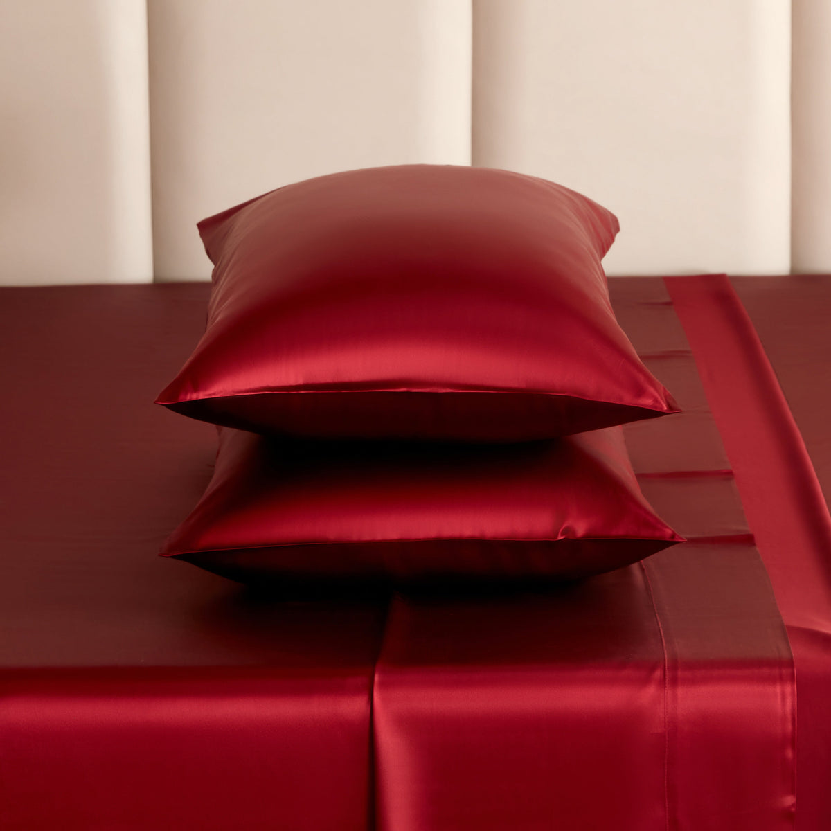 Stack of cabernet red Mulberry Park Silks pillowcases and sheets showcasing the smooth, lustrous sheen and rich color of 22 momme pure Mulberry silk bedding.