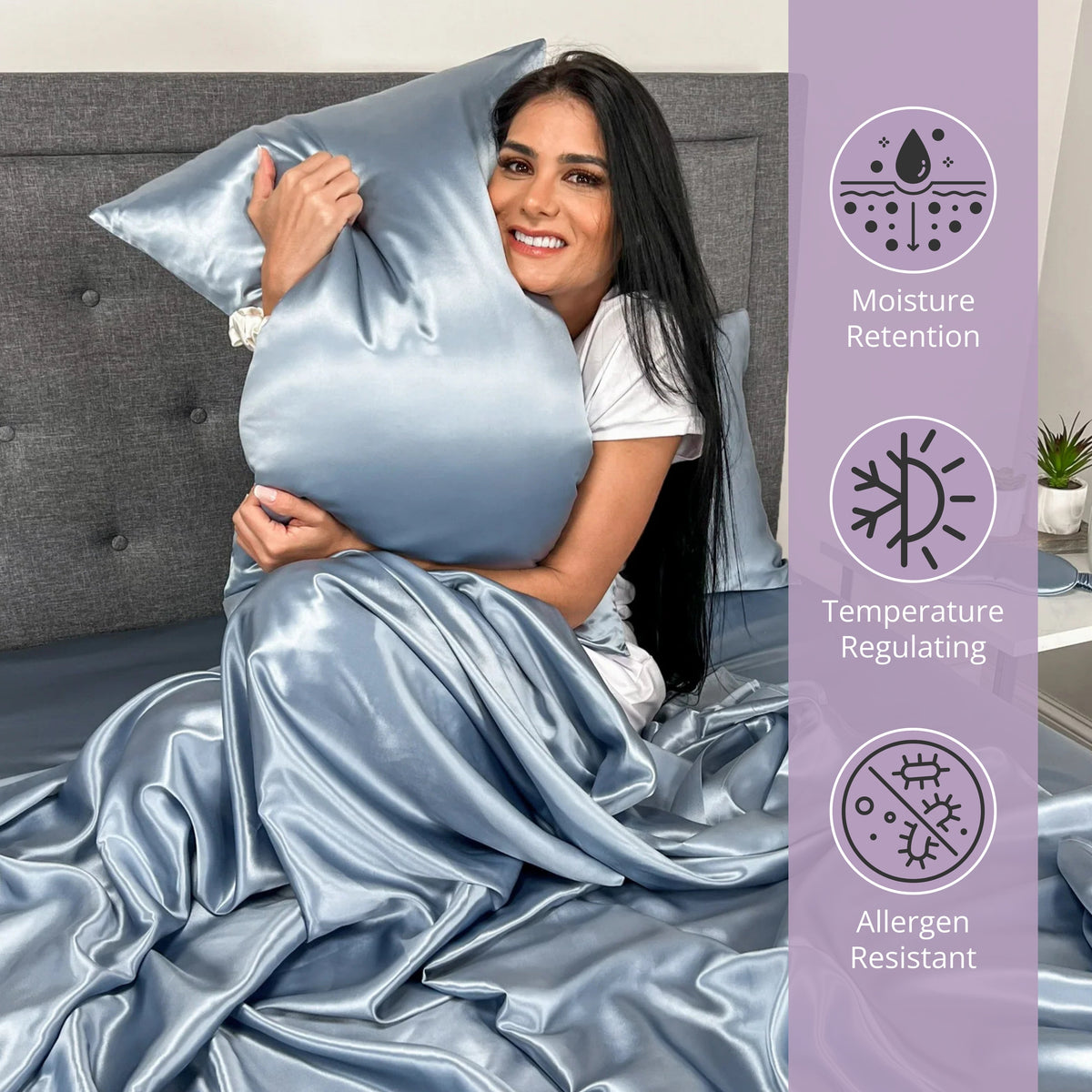 Woman sitting on bed, hugging a gunmetal silk pillow and enjoying the comfort of silk sheets