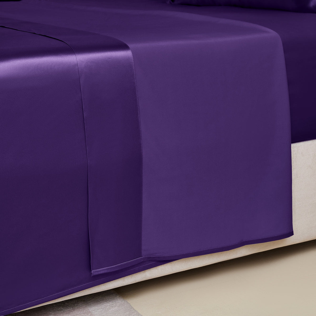 Close-up of a plum silk sheet on a bed, highlighting its delicate stitching and sheen