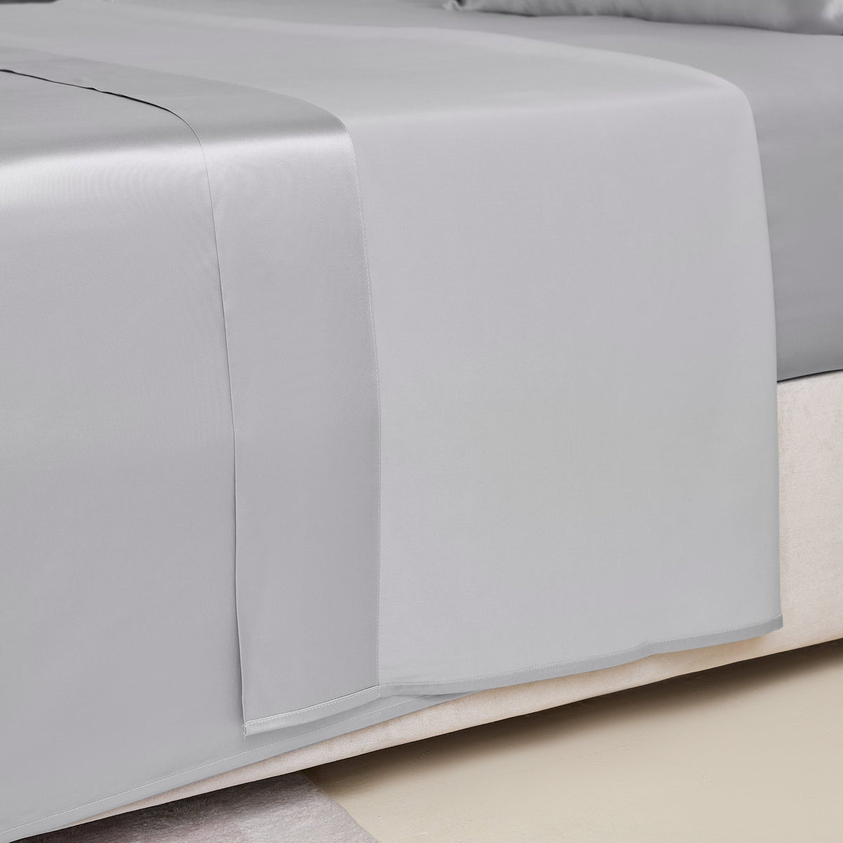 Close-up of a silver silk sheet on a bed, highlighting its delicate stitching and sheen