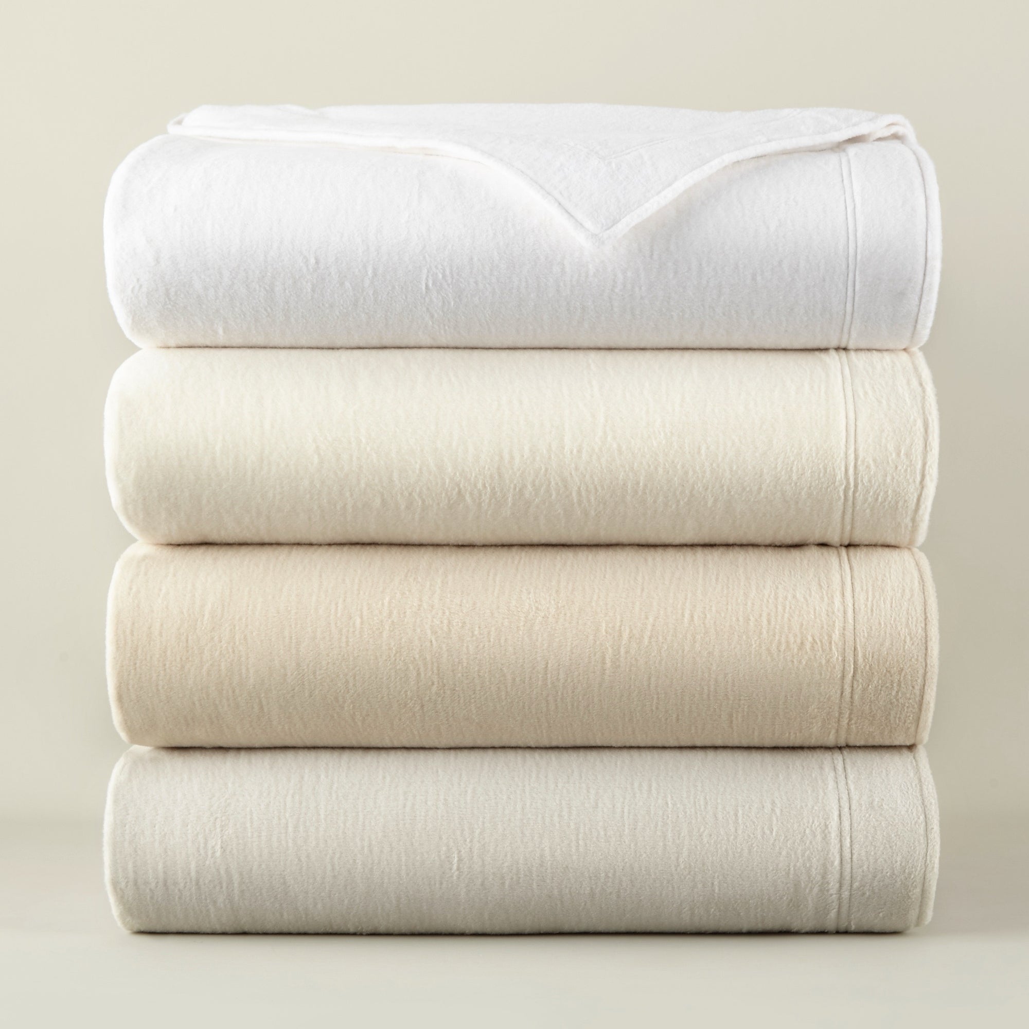 Stack of folded Peacock Alley All Seasons Framed Blankets in all colors