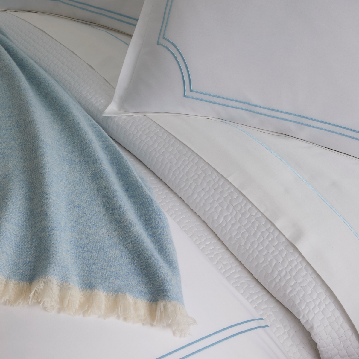 Closeup of Peacock Alley Deco Classic Embroidered Duvet Set in Sky with coordinate bedding