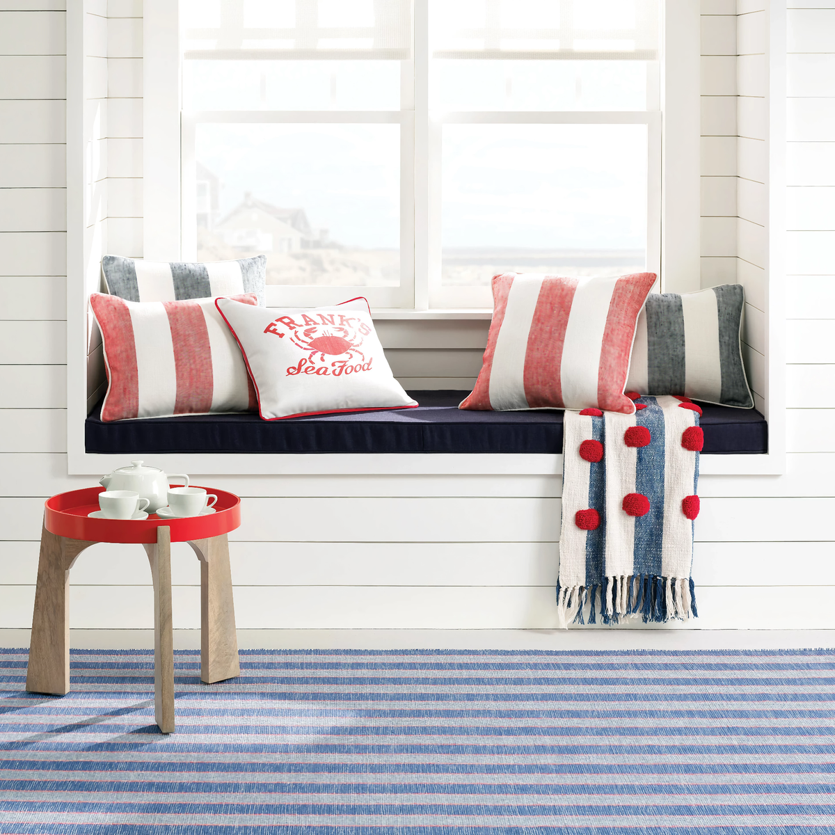 Lifestyle Image of Pine Cone Hill Awning Stripe Indoor/Outdoor Decorative Pillow in Navy and Red Color