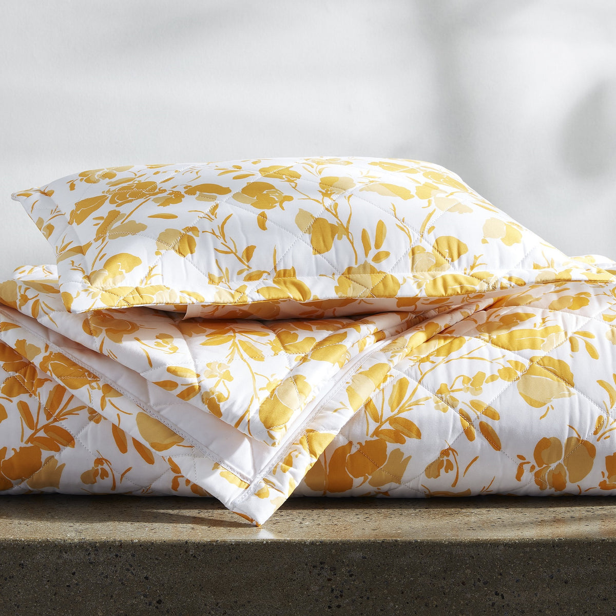 Folded Stack of Quilted Matouk Alexandra Bedding in Goldenrod Color