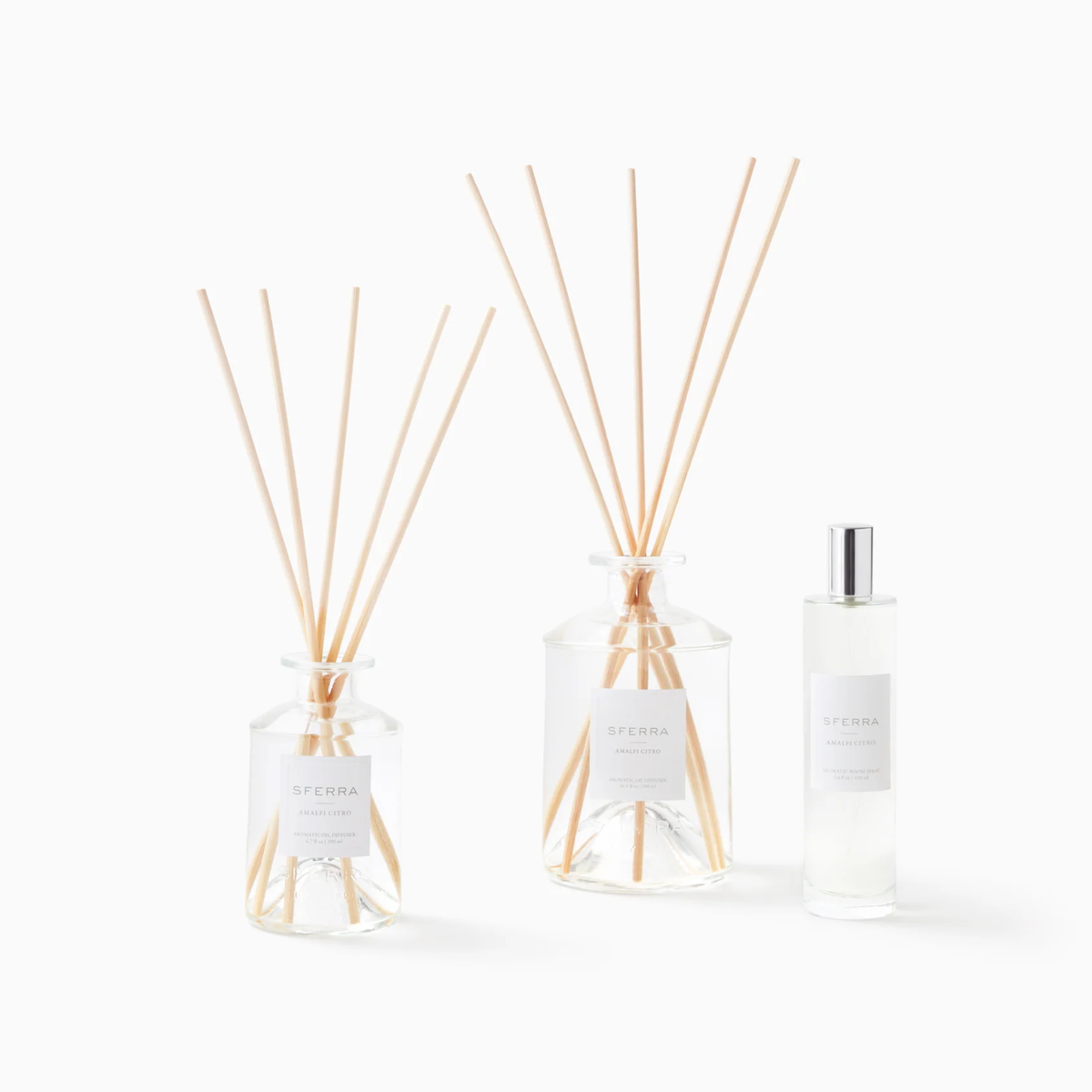 Three clear glass diffuser bottles and a spray bottle featuring SFERRA home fragrance with an Amalfi citrus scent.