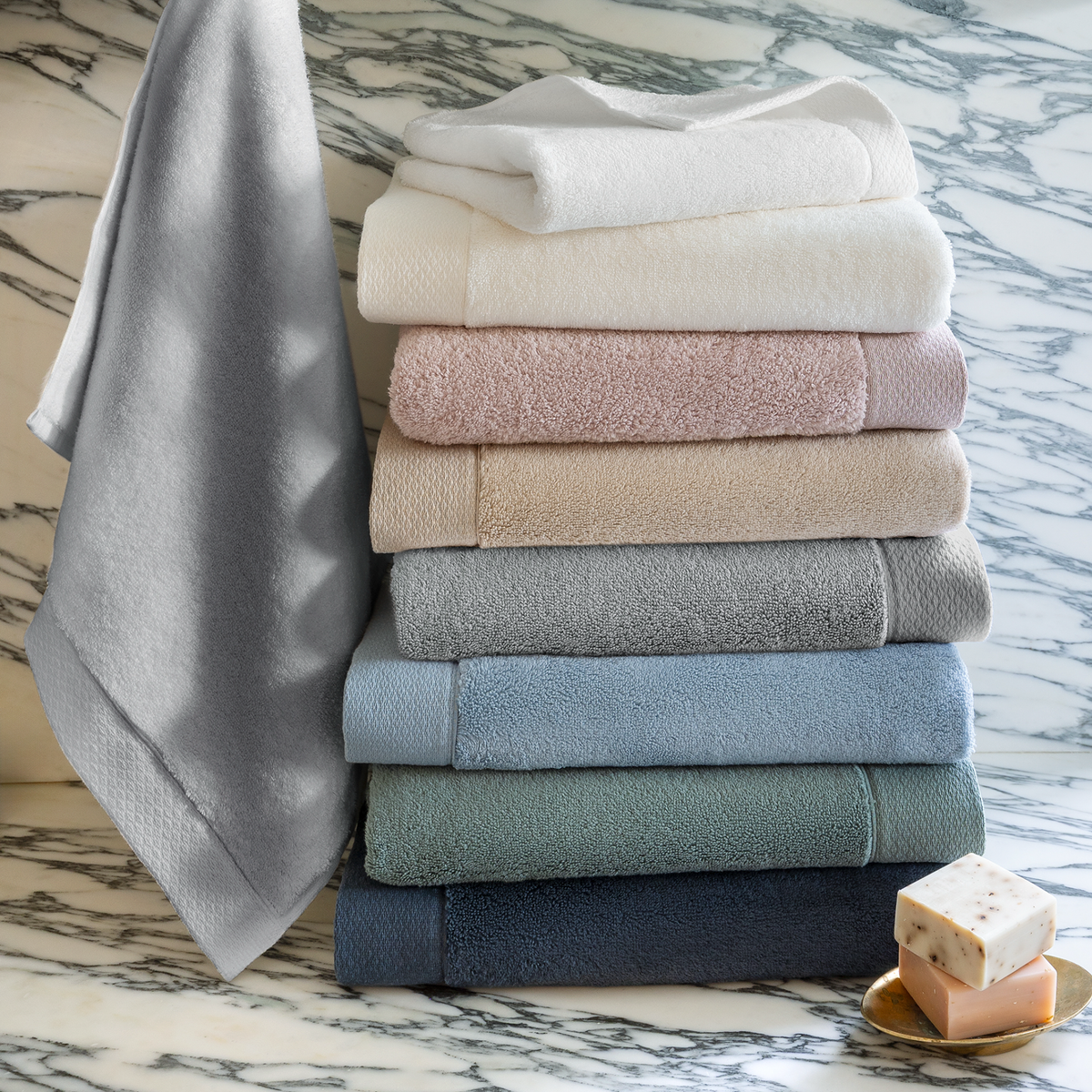 Stack of folded Scandia Home Cosima Towels in 2025 colors on a marble surface with soap.