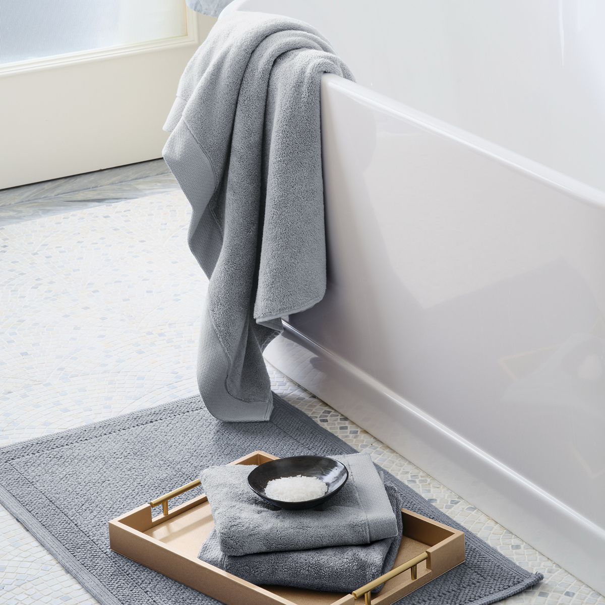 Scandia Home Cosima Towels in Alloy color on a tray on a bathroom rug.