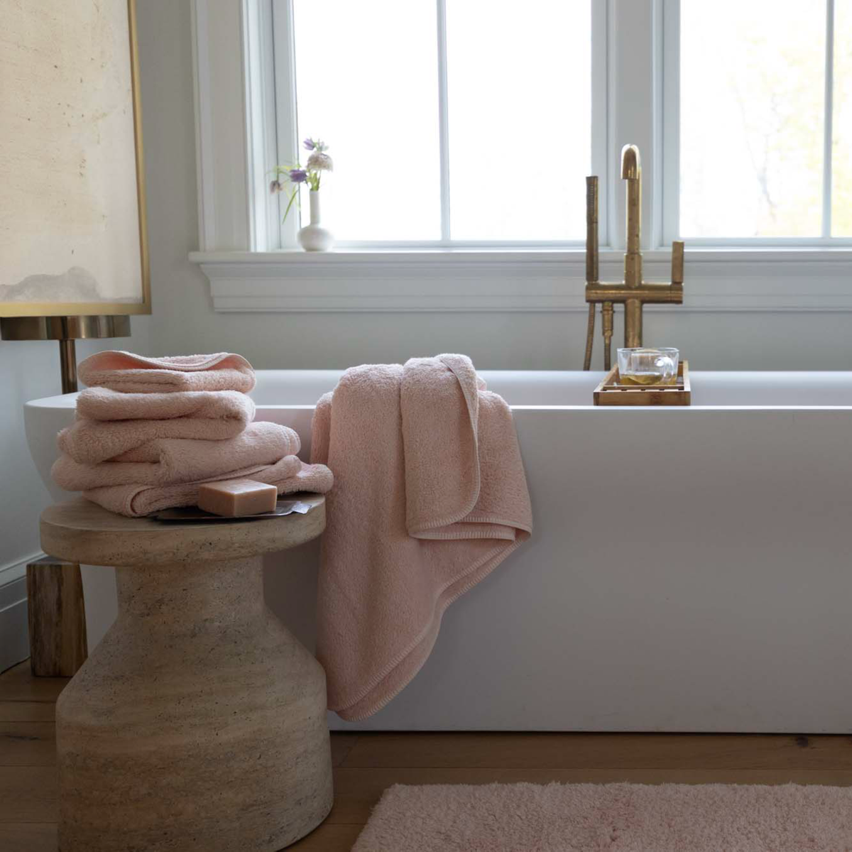 Bathroom with a white bathtub, Scandia Home Indulgence Towel in Blossom color, and a wooden stool.