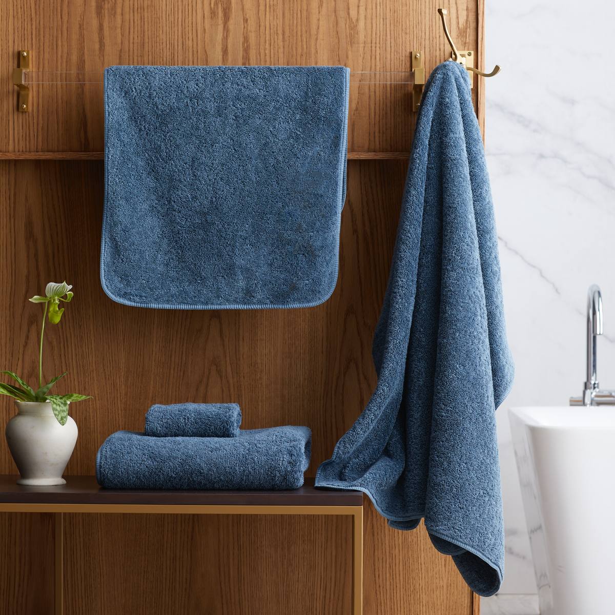 Bathroom with folded Petrol Scandia Home Indulgence Towels on a shelf and hanging on a towel rack