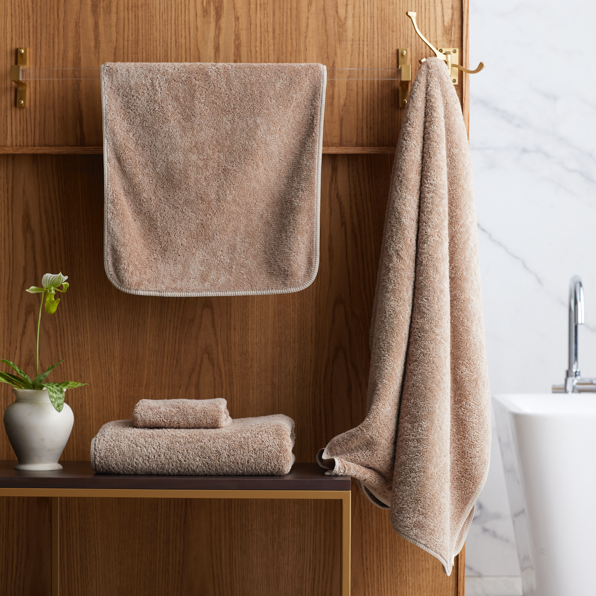 Bathroom with folded Truffle Scandia Home Indulgence Towels on a shelf and hanging on a towel rack