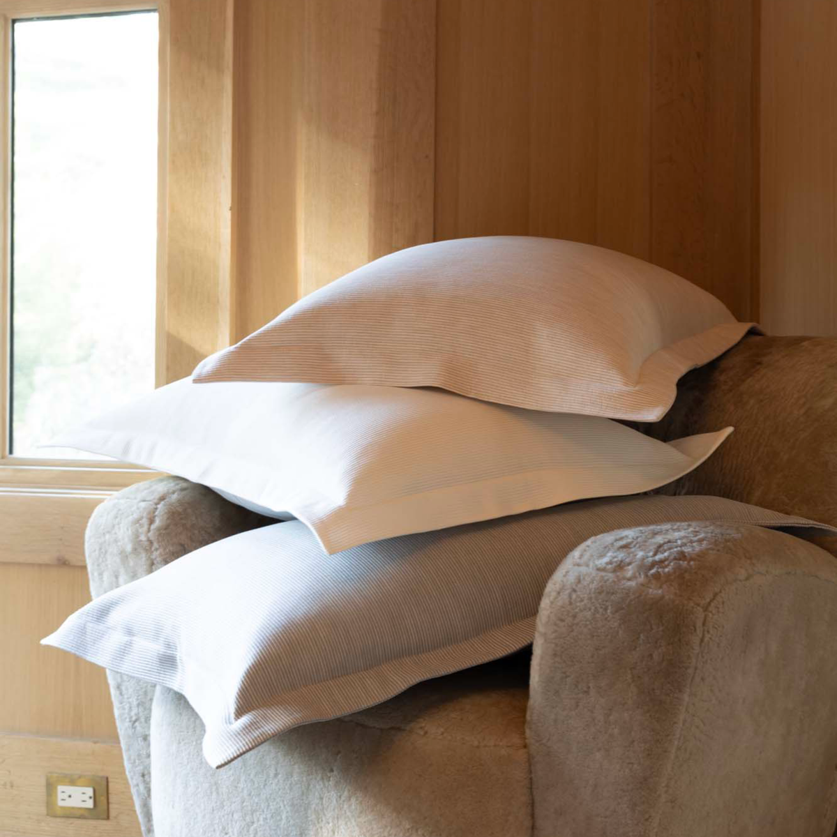 Scandia Home Lorenzo Pique Shams on a textured armchair near a window with natural light.