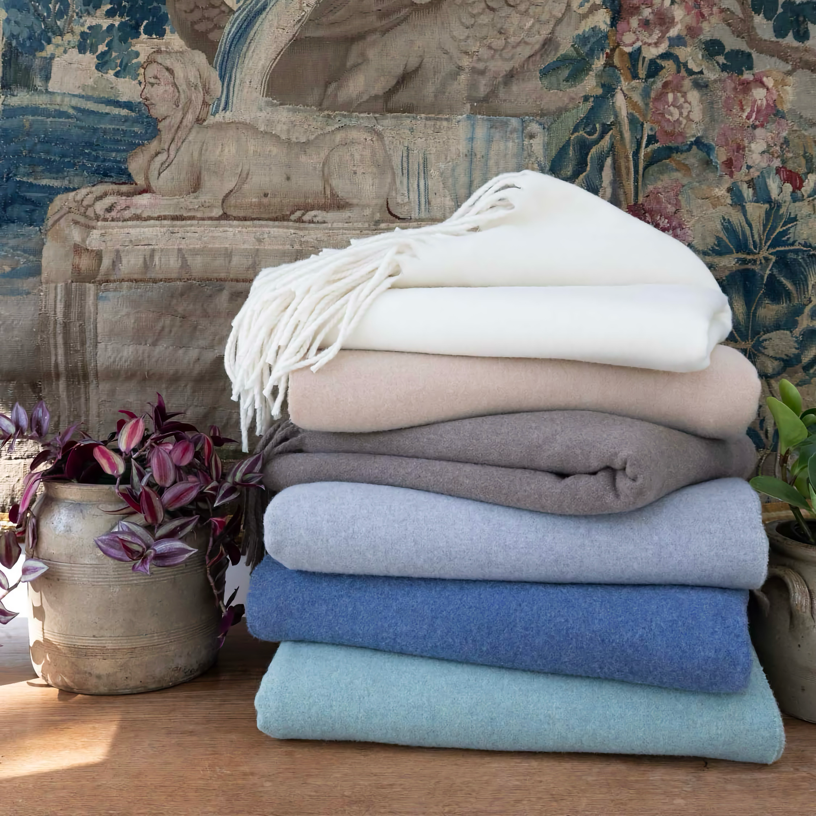 Stack of folded Scandia Home Pietro Throws on a wooden surface with decorative background