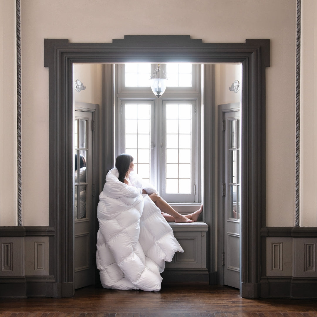 Model wrapped in a Scandia Home Chamonix comforter looking out a window