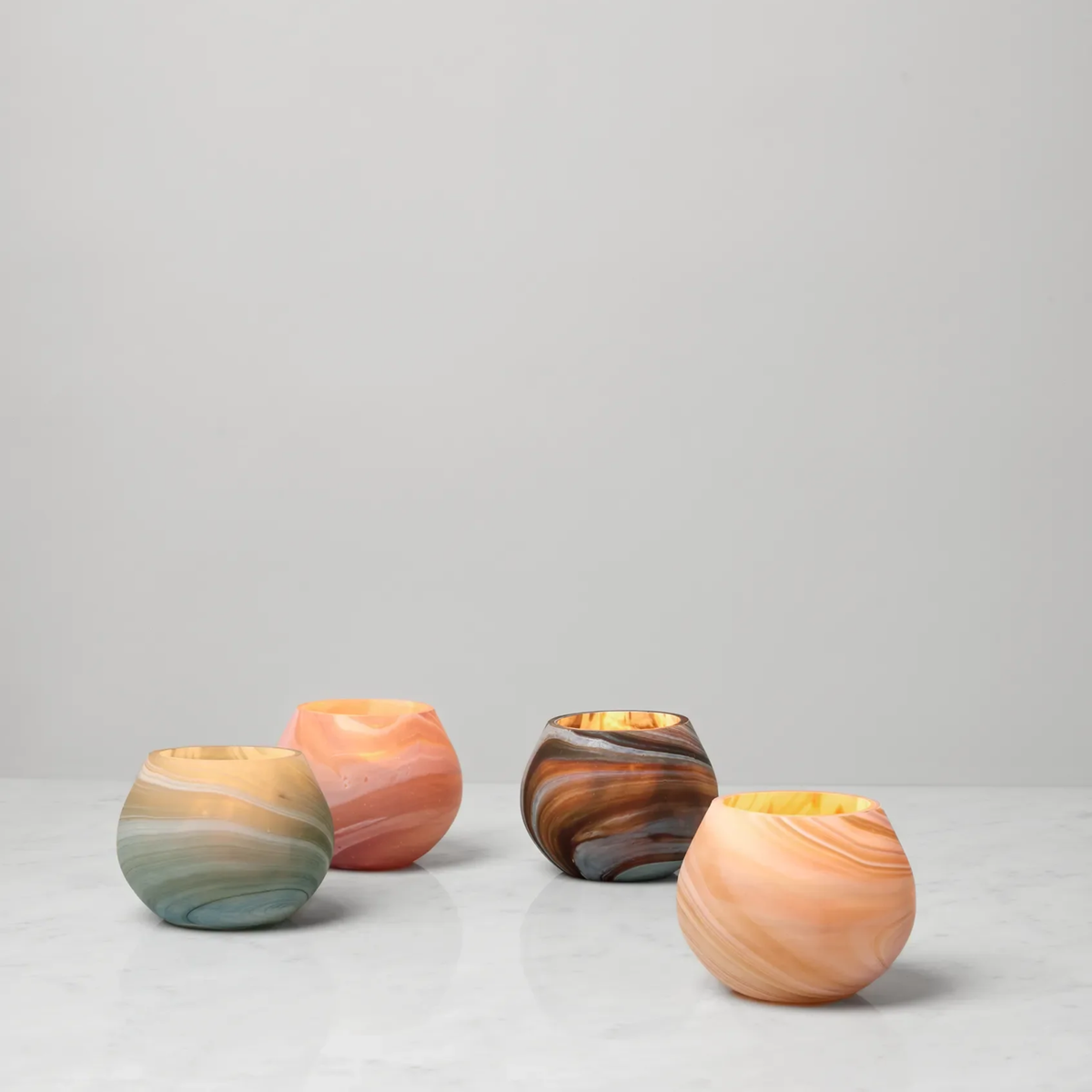 Four round, Sferra Giove Marbled Votive Holders in pastel and earthy tones create a unique home decor accent