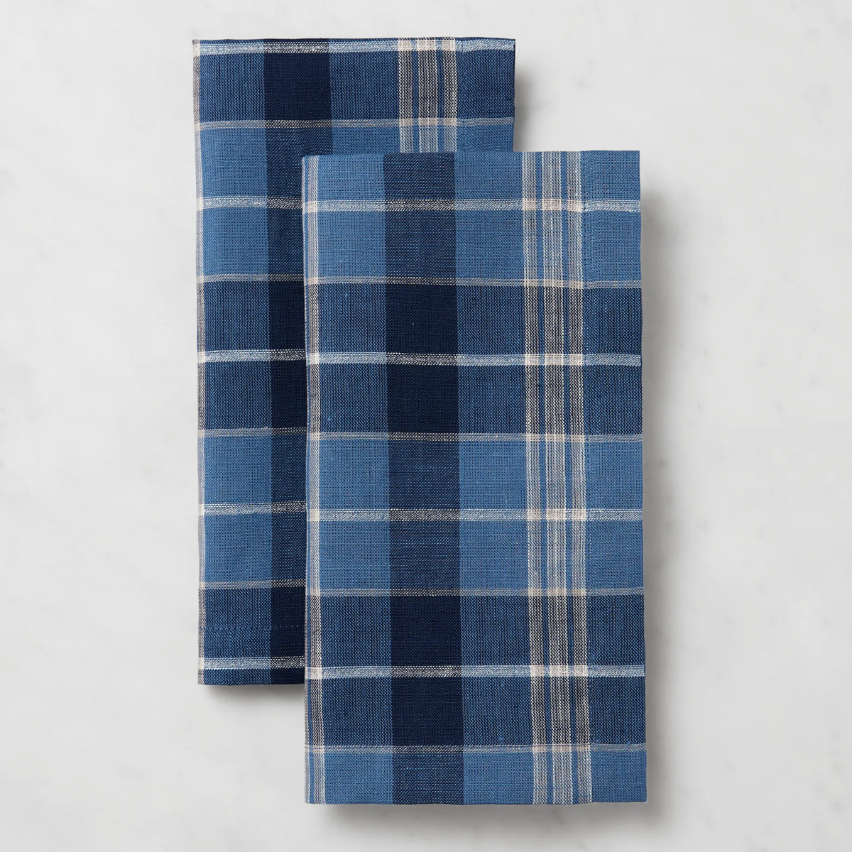 Two folded Sferra Masseria Dinner Napkins in Cadet and Navy colors rest side by side, perfect for autumnal table decor