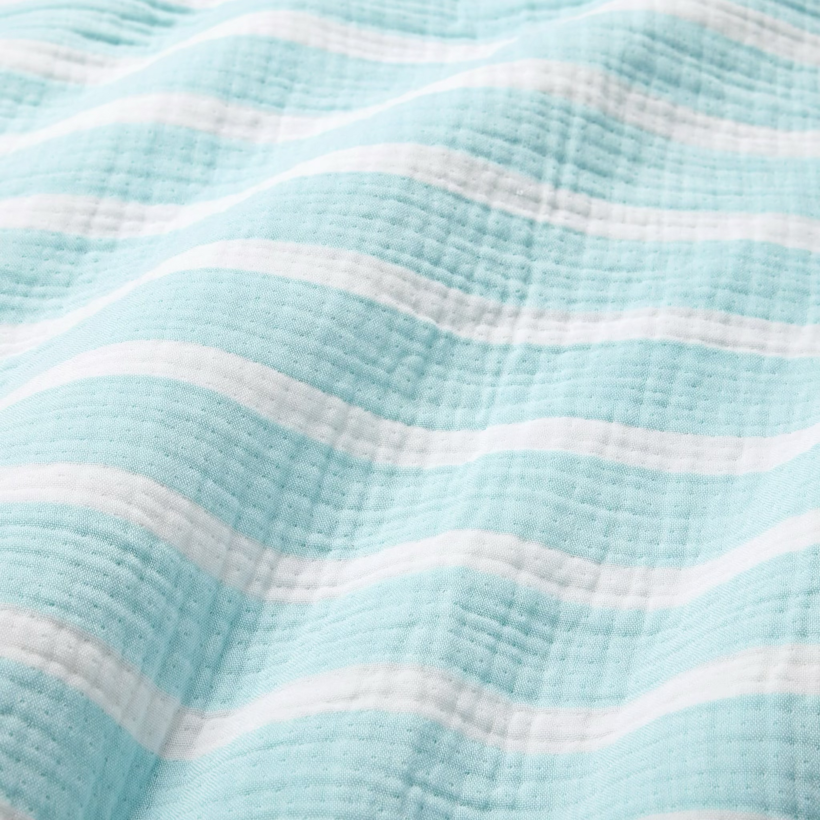 Three striped towels—blue, red, and green—hang on hooks, each a luxury cotton beach towel by the sunny window.